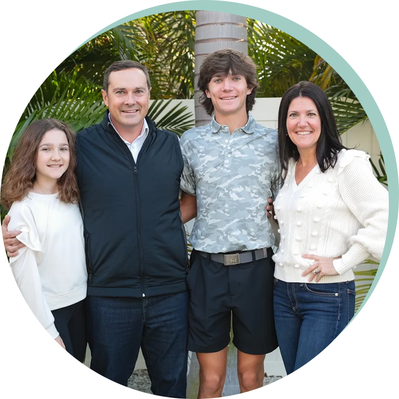 A family posing for a picture in front of palm trees.