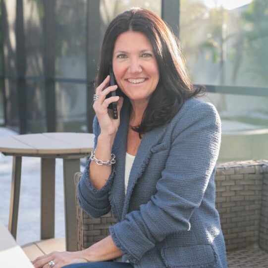 A woman sitting on the ground talking on her phone.